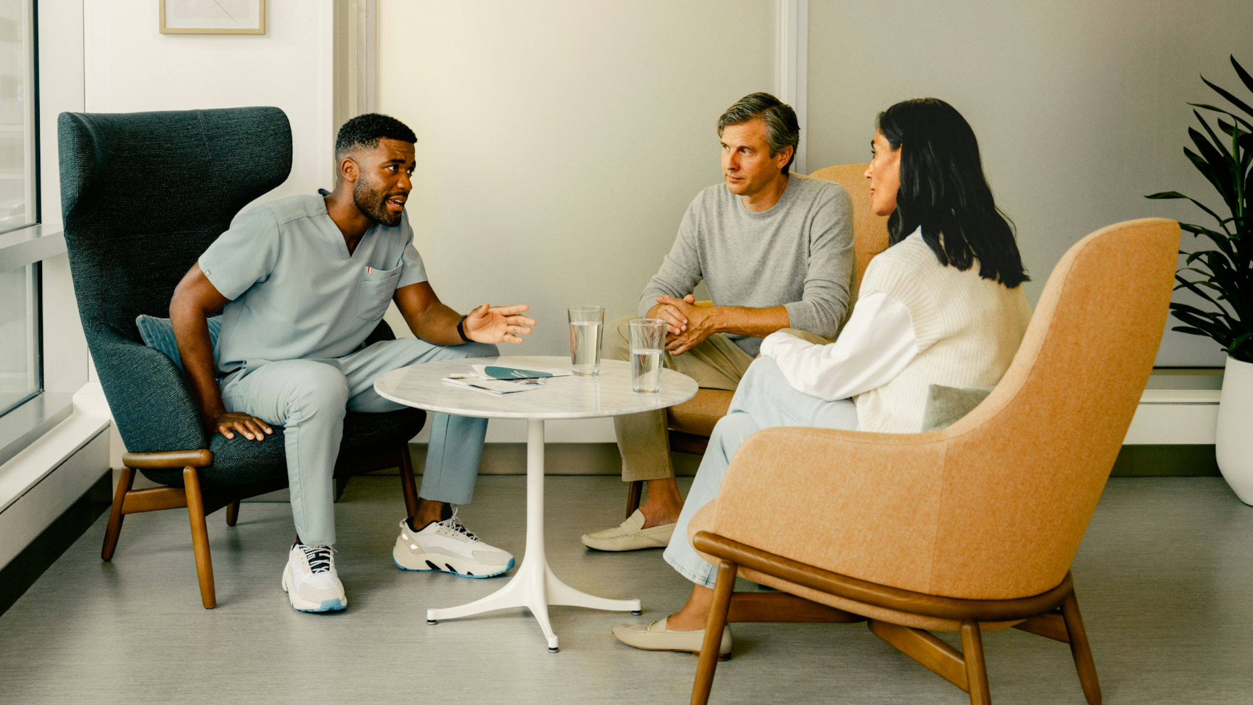 Male nurse consulting with a female patient and her male family member in a casual setting.