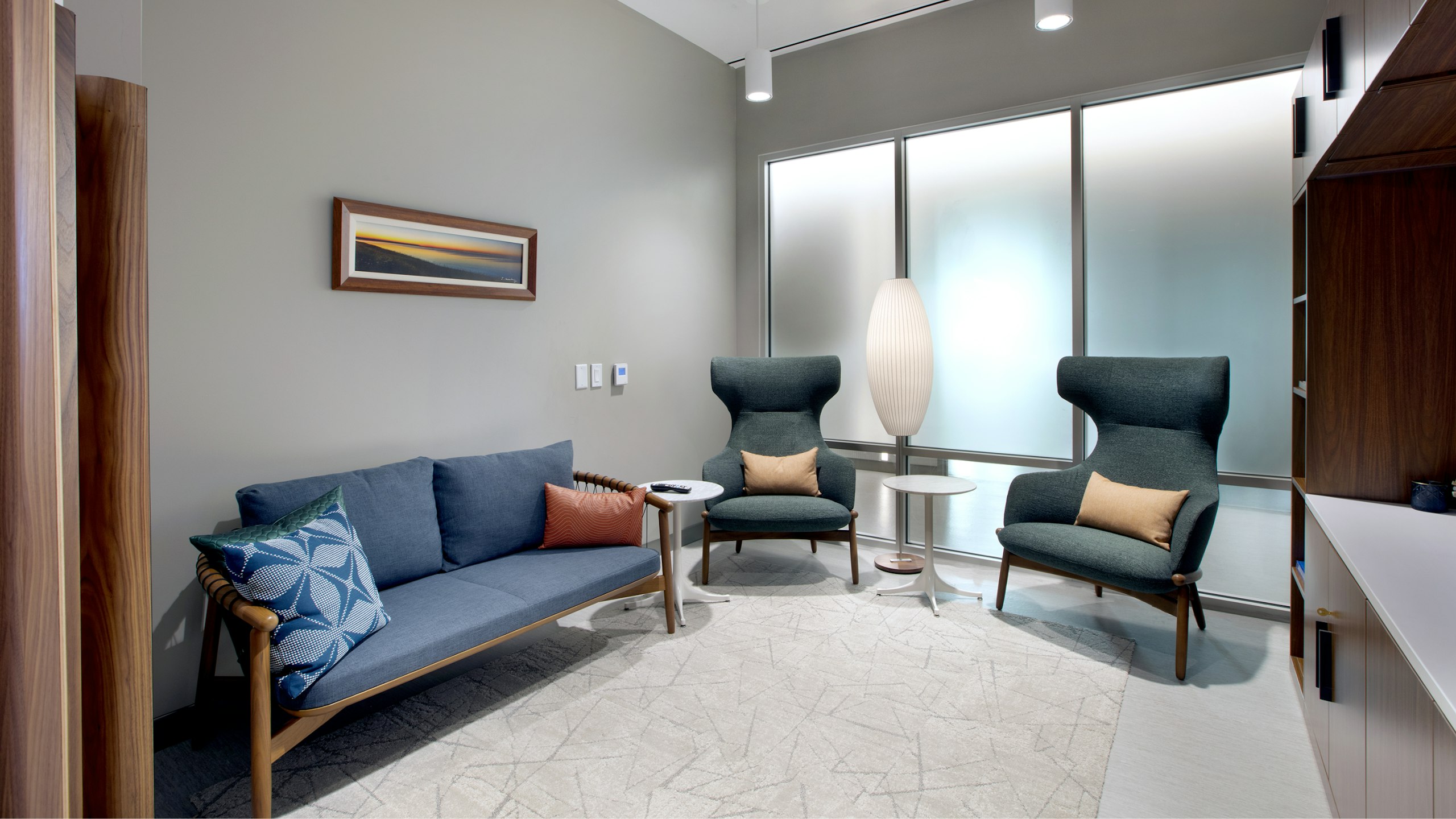 A waiting room with a blue sofa and blue chairs at BAMF Health
