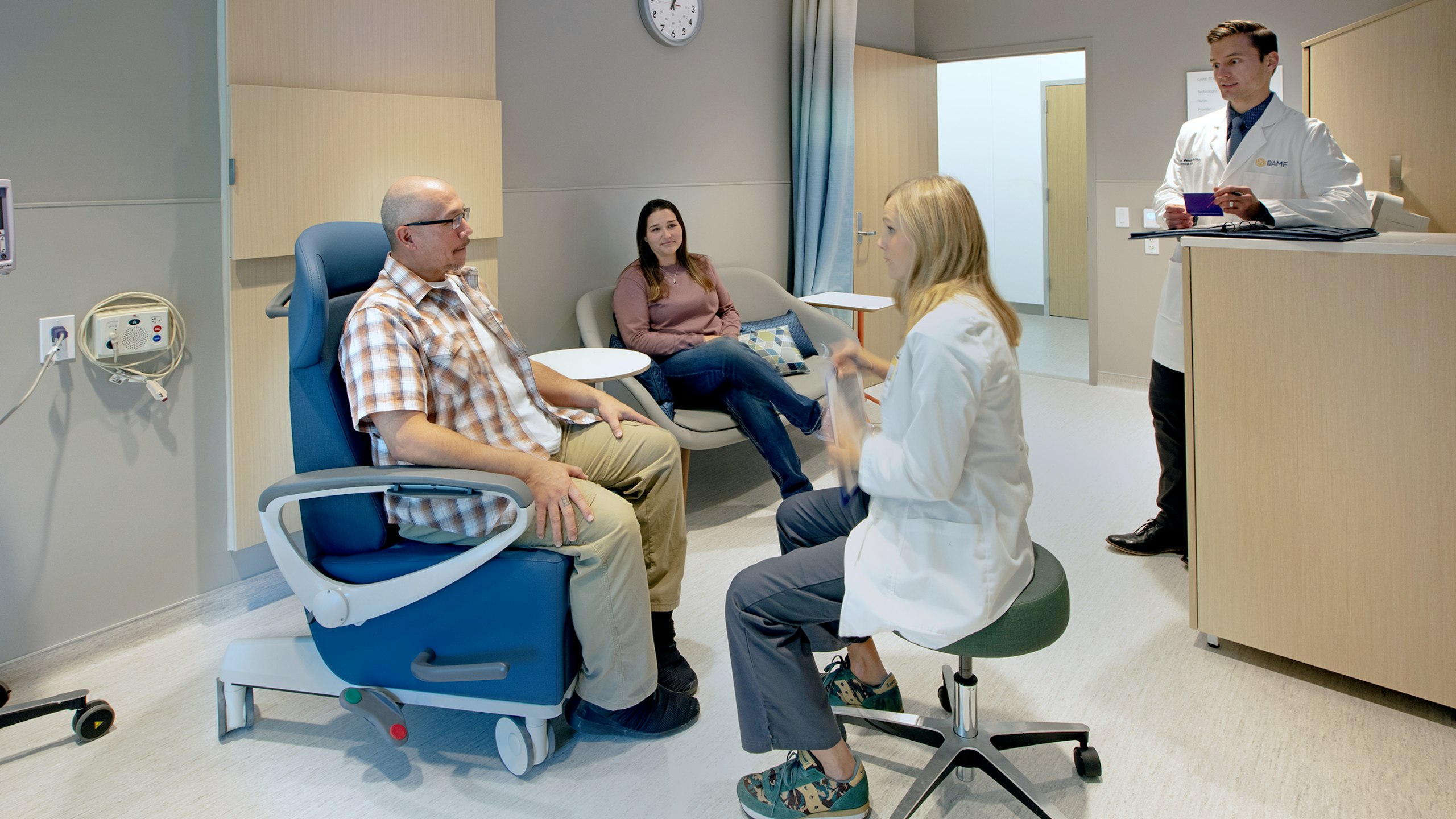 Two doctors visiting a patient and their family in an exam room at BAMF Health